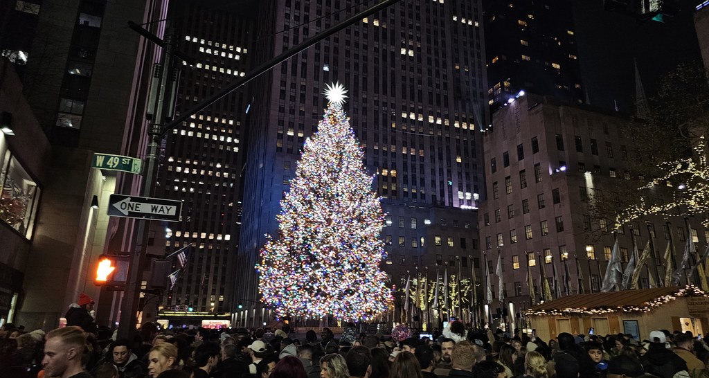 Visitors wearing warm winter coats and layers viewing Rockefeller Center Christmas tree